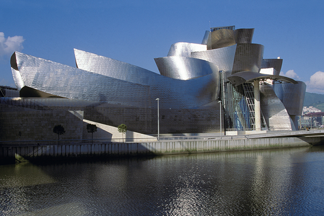 フランク・ゲーリー「ビルバオ・グッゲンハイム美術館」 1997年（スペイン・ビルバオ）　20世紀のモダニズム建築の限界を乗り越えようとする「脱構築建築」を代表する建築家の一人で、アンバランスかつ複雑な形態の建築を展開。代表作であるビルバオ・グッゲンハイム美術館の複雑な外観形状は、航空機などの設計に使われる当時最先端のCADシステムで構造計算を行い、実現したもの。（Photo：Bill WASSMAN／Getty Images）