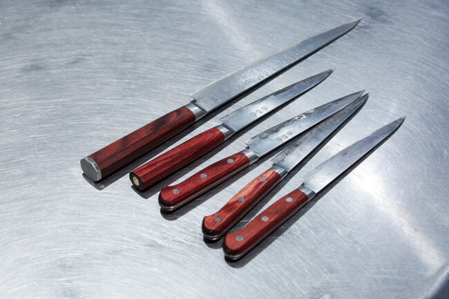 刃物の産地、福井県越前市の高村刃物製作所の包丁。手前から4本のペティナイフ（スーパーゴールドペティ150mmワインレッドハンドル）。夏子からétéの刻印に。奥の筋引きは、鍛造粉末不錆鋼ダマスカス「打雲 花（うちぐも はな）」ワインレッドハンドルのété仕様。