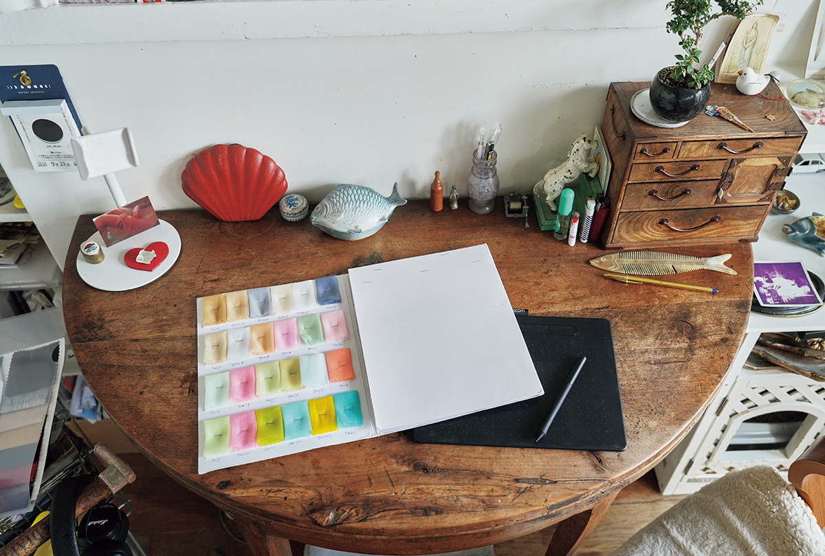 「オーガンジーの生地見本とiPadは仕事の必需品」。アンティークの小物に混ざって、表情豊かな魚のオブジェも見守っている。