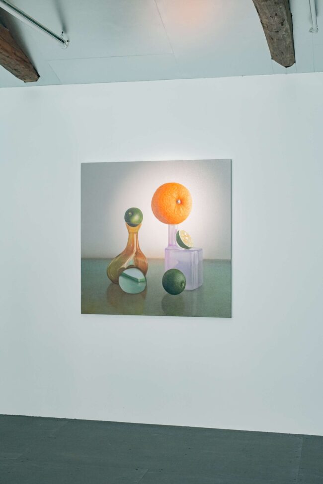 《Forgotten Verses 柚子と酢橘》（2025年 油彩／キャンバス 100×100cm）モチーフを自ら選ばないことをルールに構成した作品。印象的なフラワーベースは大学の学生がお土産にくれたもの。周囲に配置された柚子やすだちは、海外ゲストが来日の際にホテルに忘れてしまったものだそう。「西洋絵画でよく描かれるオレンジに似ていながら、柚子やすだちは主役になったことがない。『忘れ物』というエピソードもふくめ、かわいいモチーフだと思いました」