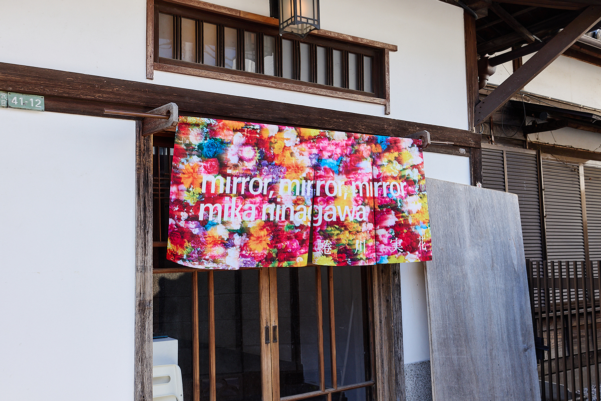 展覧会『mirror, mirror, mirror, mika ninagawa』より。古民家のたたずまいに極彩色ののれんが目を惹くエントランス風景。